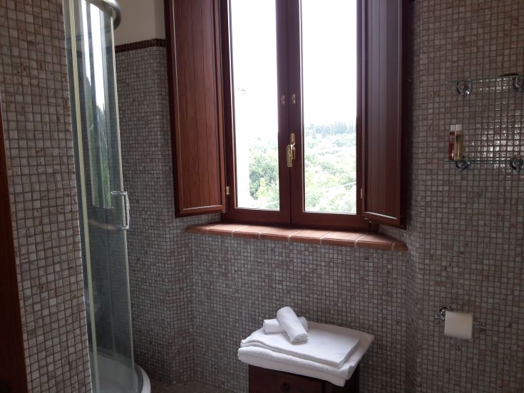 Ein einfaches Badezimmer mit Dusche, sauberen Handtüchern und Blick auf die Landschaft. Eine gemütliche Ecke zum Entspannen.