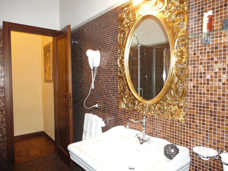 Elegantes Badezimmer mit einem goldenen Spiegel und dunklen Fliesen, in einer gepflegten Umgebung.