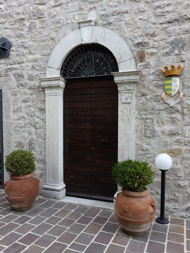 Holztür an einer Steinfassade mit Pflanzen, ein Eingang, der die Geschichte des Ortes widerspiegelt.