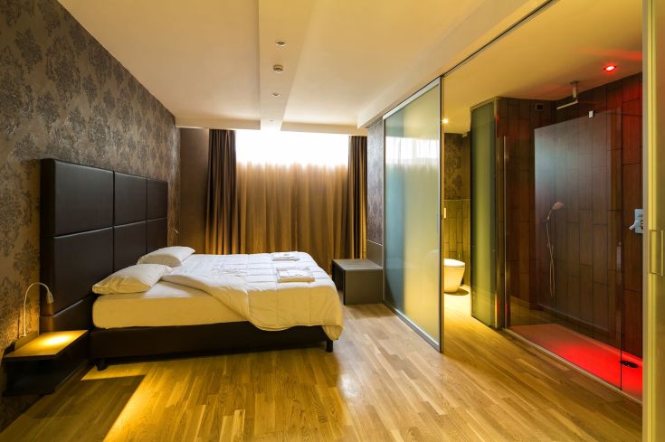 Chambre d'hôtel simple et confortable avec salle de bain en verre et une fenêtre qui éclaire l'espace.