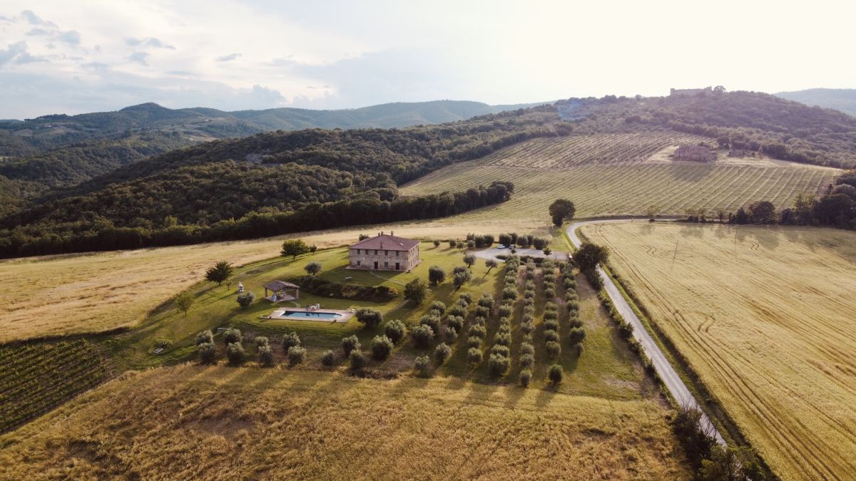 Une vue d'une ferme typique de l'Ombrie, entourée de verdure luxuriante et de collines douces.
