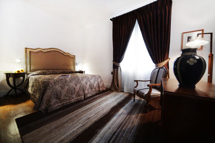 Camera semplice con letto matrimoniale e arredi curati, adatta per un soggiorno tranquillo.