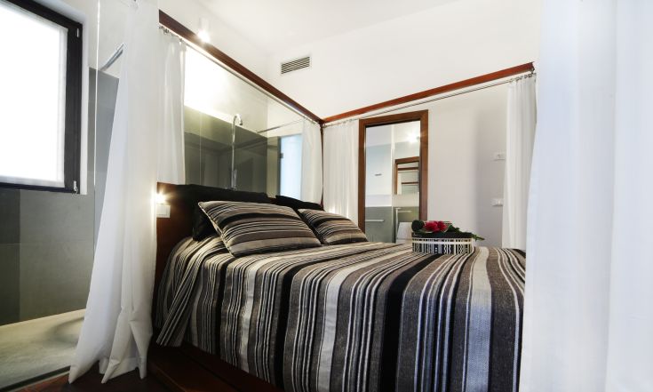 Camera con letti a righe, specchio e dettagli in legno. Atmosfera semplice e accogliente.