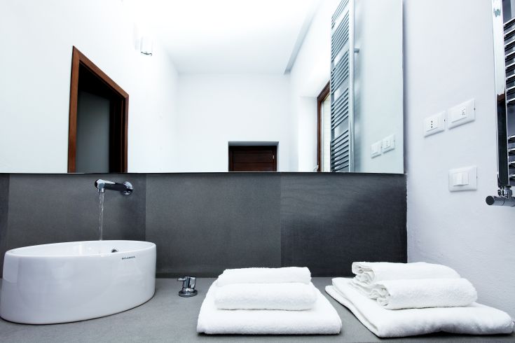 Un bagno sobrio con un lavandino moderno e asciugamani bianchi ben sistemati.