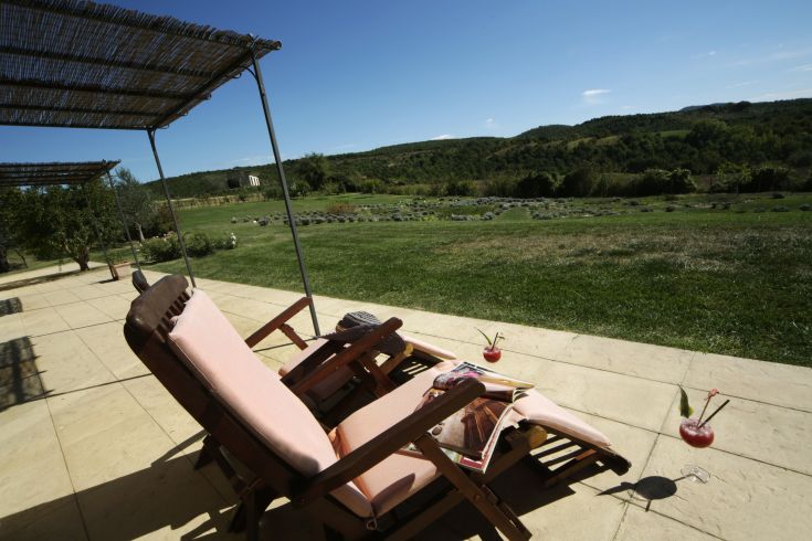 Panorama dal patio di un resort, con lettino e cocktail, circondato dalla vegetazione dell'Umbria.