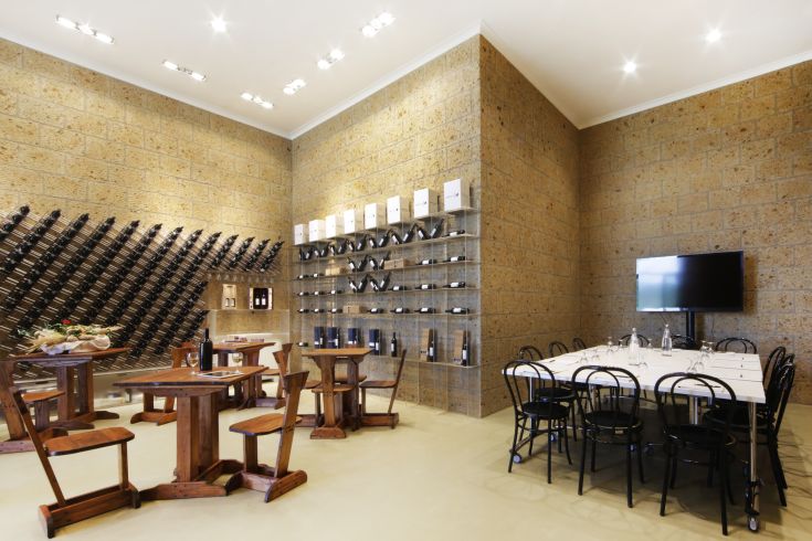Ampia sala dedicata alla degustazione di vini, con tavoli in legno e scaffali per bottiglie, le pareti sono rivestite in pietra.