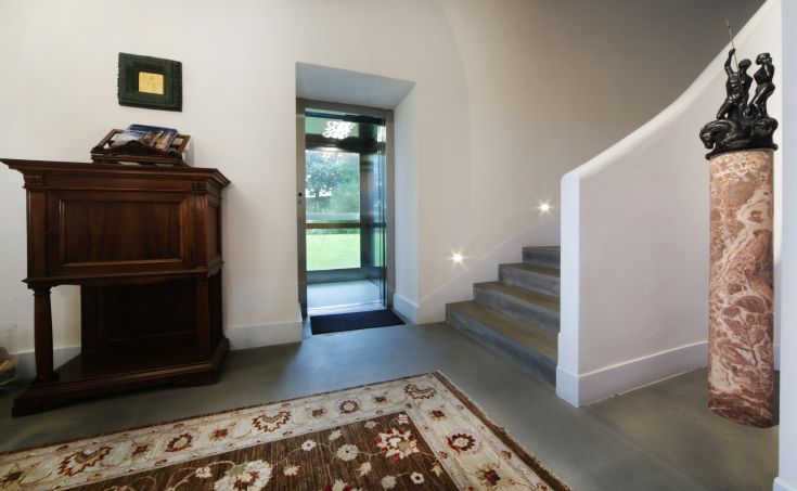 Ingresso semplice con scala in pietra, arredato in modo sobrio con alcuni dettagli decorativi.