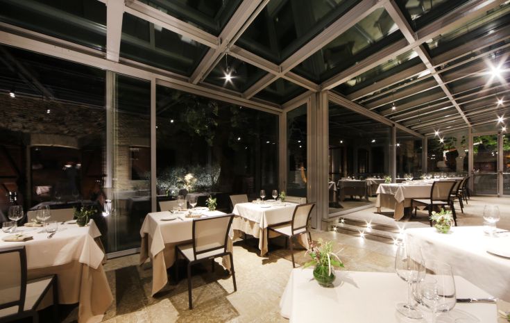 Locale con grandi vetrate che si affacciano su un giardino, adatto per cene formali.