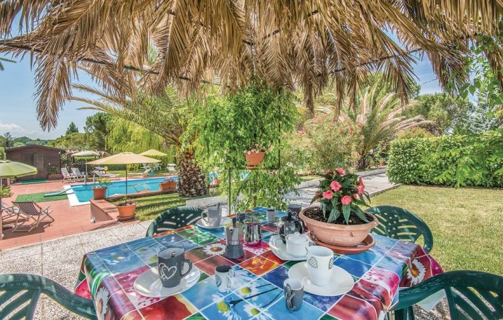 Un tavolo all'aperto accanto a una piscina, circondato da piante verdi. Un luogo tranquillo per rilassarsi.