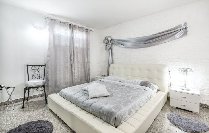 Camera confortevole con letto matrimoniale, tende leggere e mobili contemporanei.