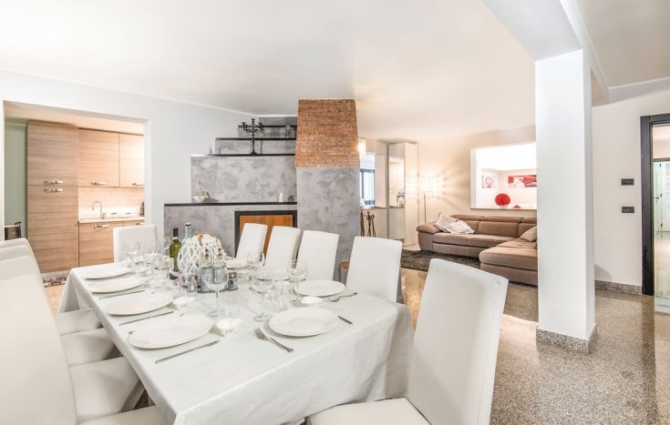 Un soggiorno moderno con un grande tavolo da pranzo, adatto per una cena elegante, immerso in un ambiente accogliente.