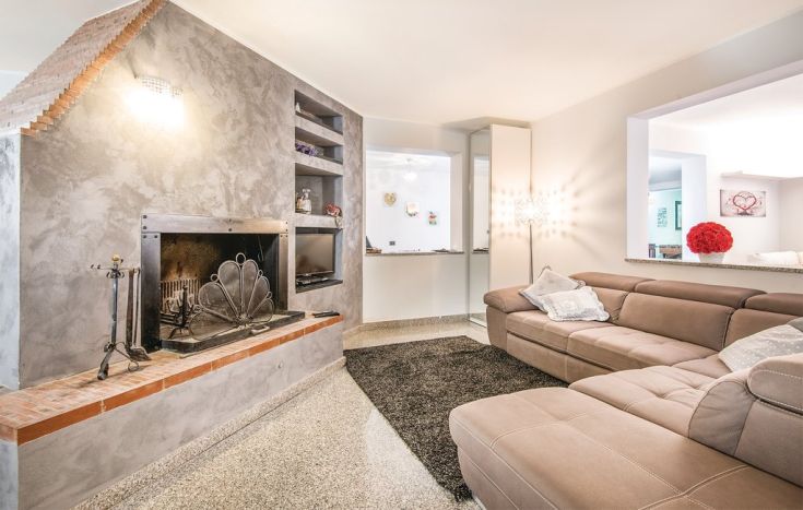 Un soggiorno semplice con camino, un divano e alcuni elementi decorativi.