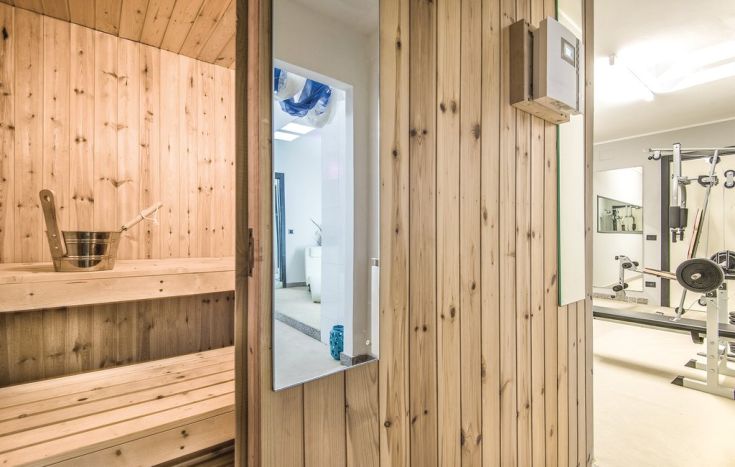 Interno di una spa con sauna in legno e attrezzature fitness in un ambiente rilassante.