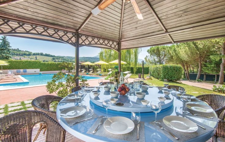 Un tavolo all'aperto apparecchiato, affacciato su un paesaggio naturale tranquillo.