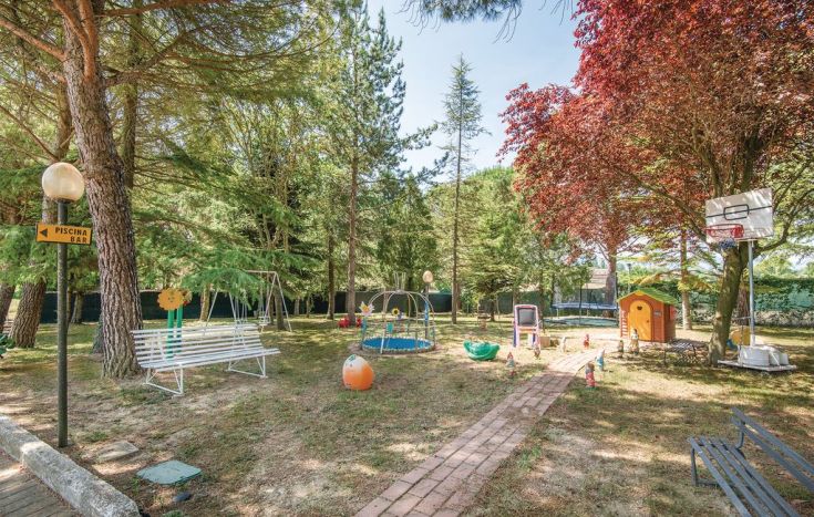 Un'area giochi circondata da alberi, con panchine e attrezzature per bambini.