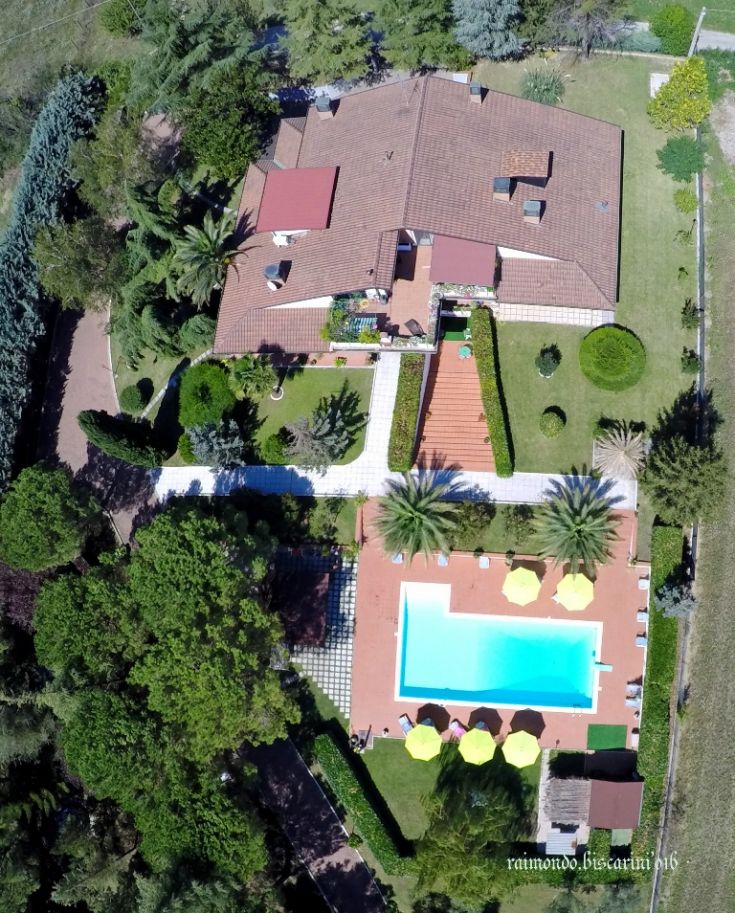 Immagine di una villa con piscina circondata da alberi e piante, ideale per trascorrere momenti di relax.