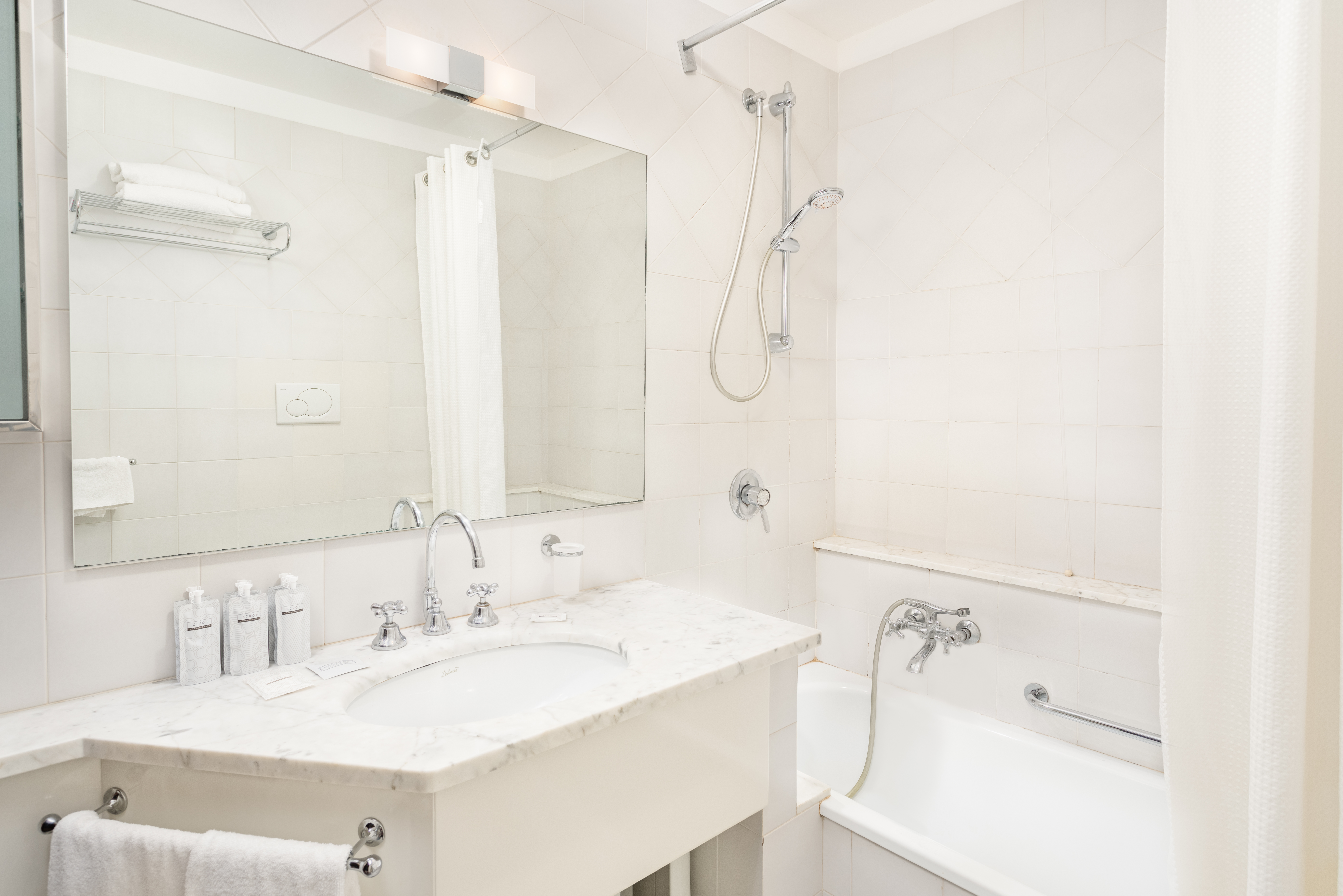 Ein schlichtes Badezimmer mit hellen Fliesen, einem Marmorspülbecken und einer Badewanne. Ein schlichtes und funktionales Raum.
