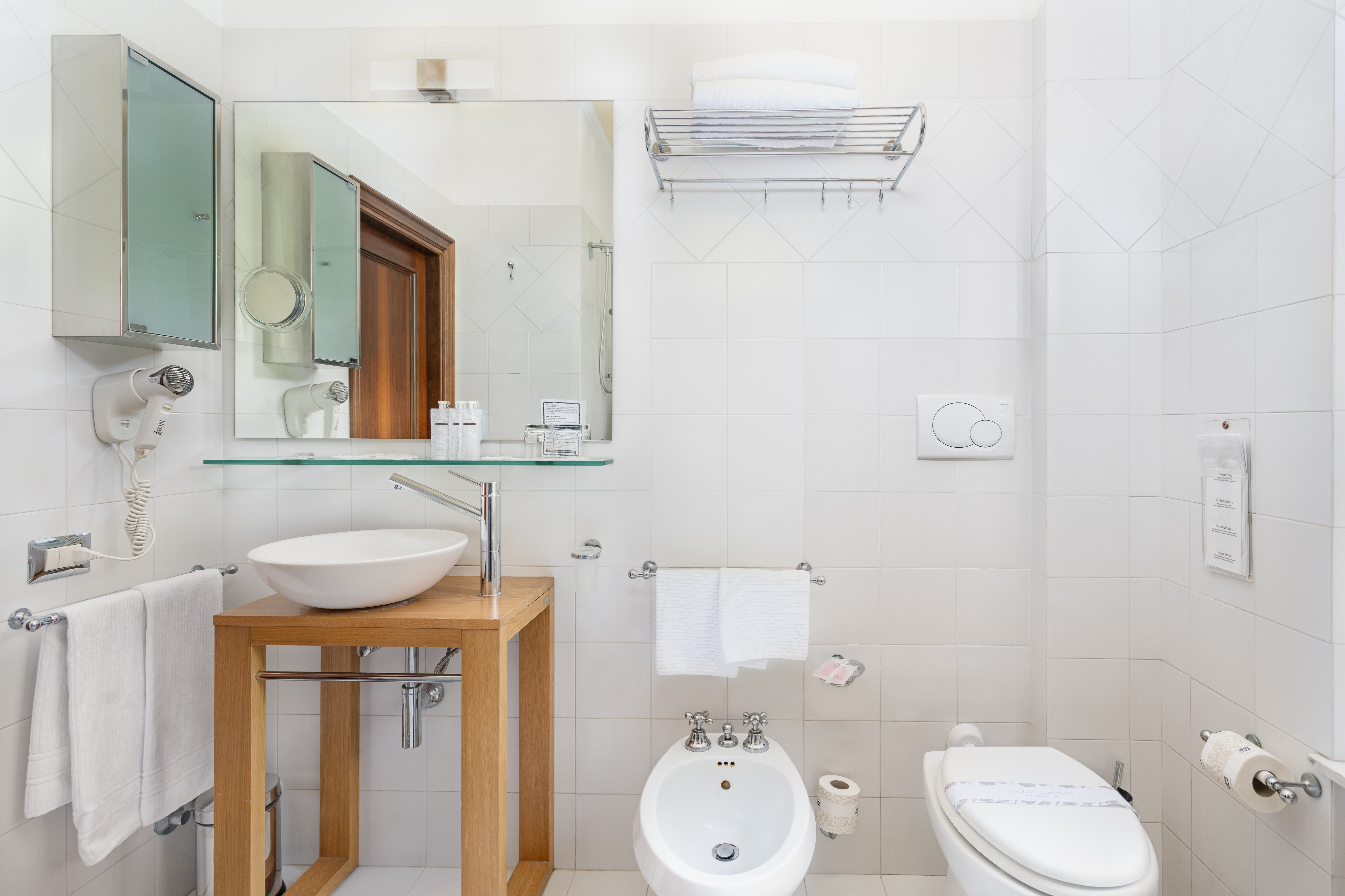 Modernes und funktionales Badezimmer mit weißen Armaturen und hölzernen Details. Helle und einladende Räumlichkeit.