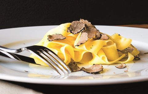 Un piatto di pasta fresca condita con scaglie di tartufo.