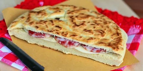 Una torta al testo con salumi e formaggi, ideale per momenti conviviali e pasti informali.