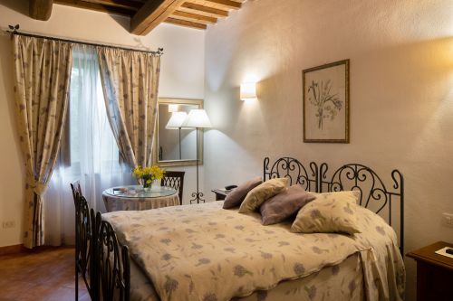 Camera semplice con letto matrimoniale e arredi sobri, adatta per un soggiorno confortevole.