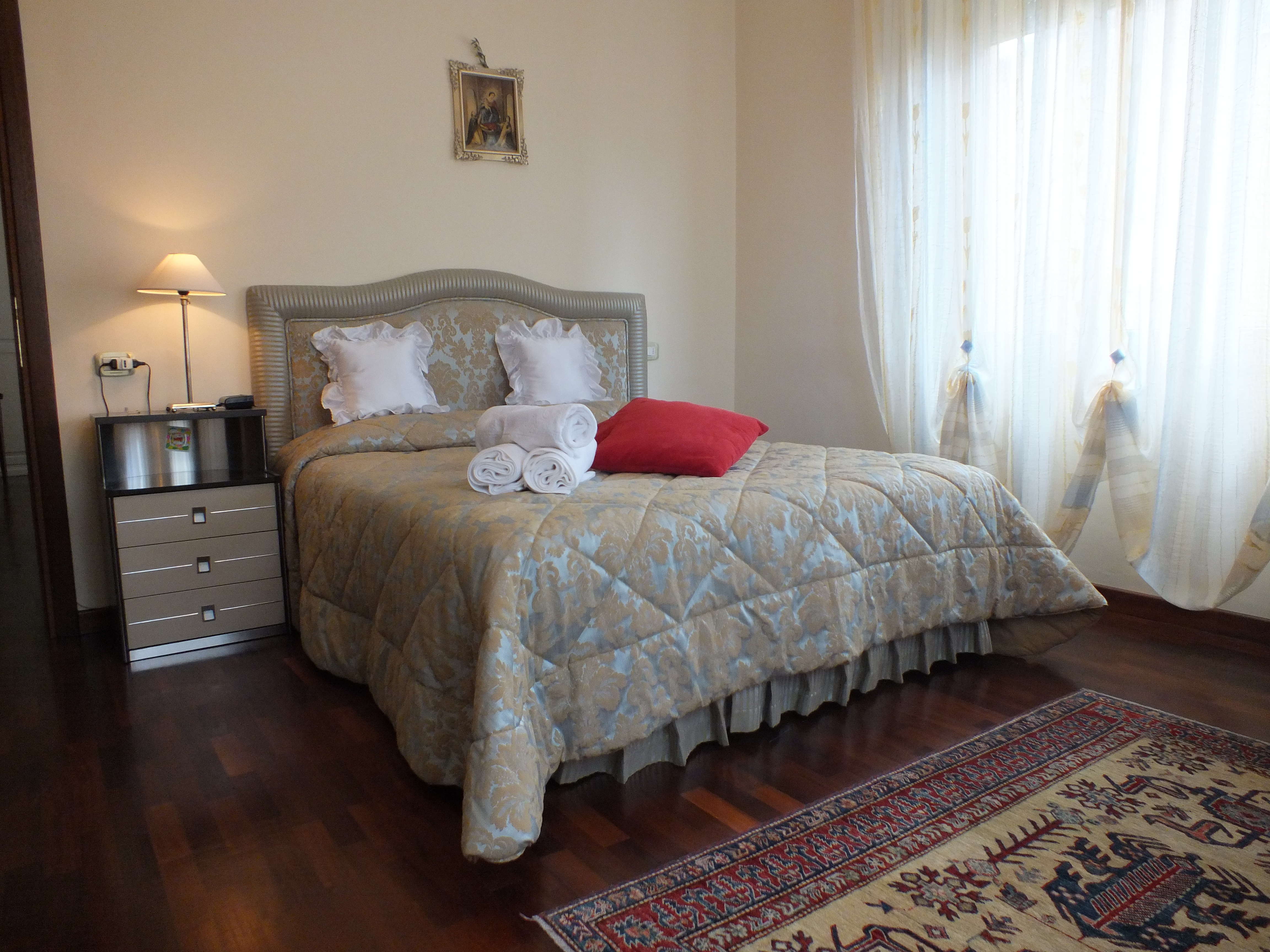 Camera semplice e ampia con letto matrimoniale e decorazione sobria.