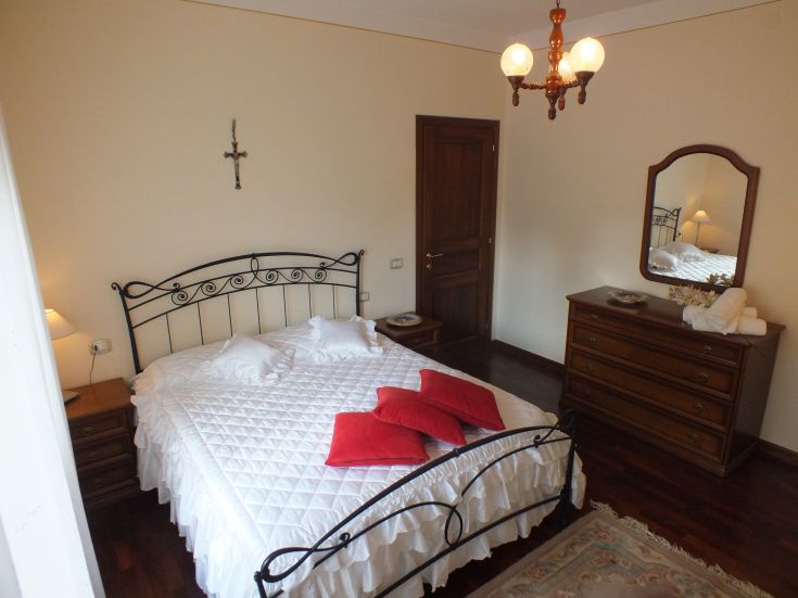 Camera da letto confortevole con letto matrimoniale, armadio e specchio. Atmosfera calda e serena.