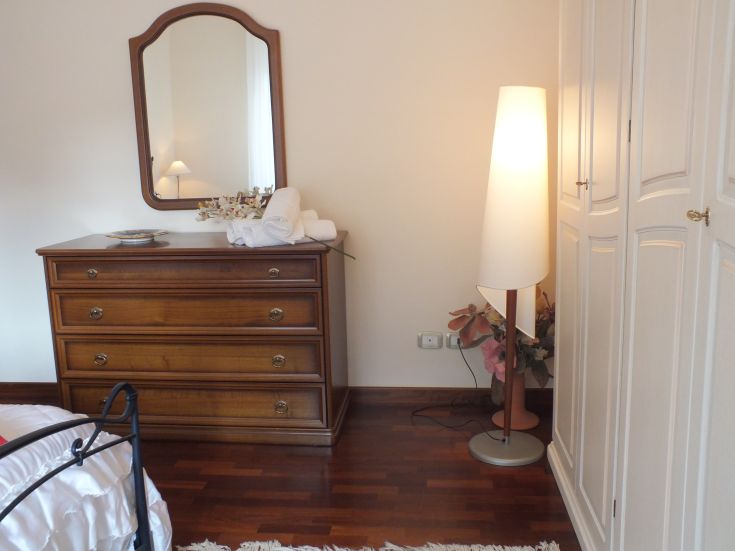 Un angolo accogliente di una camera da letto con un comò in legno e una lampada raffinata.