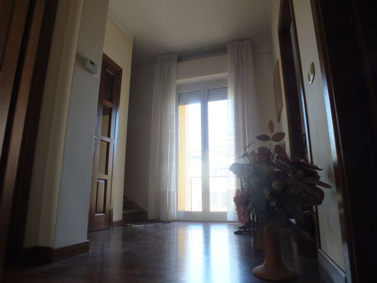 Interno luminoso con porte e finestre aperte, arredato con un semplice vaso di fiori, che offre un'atmosfera accogliente.