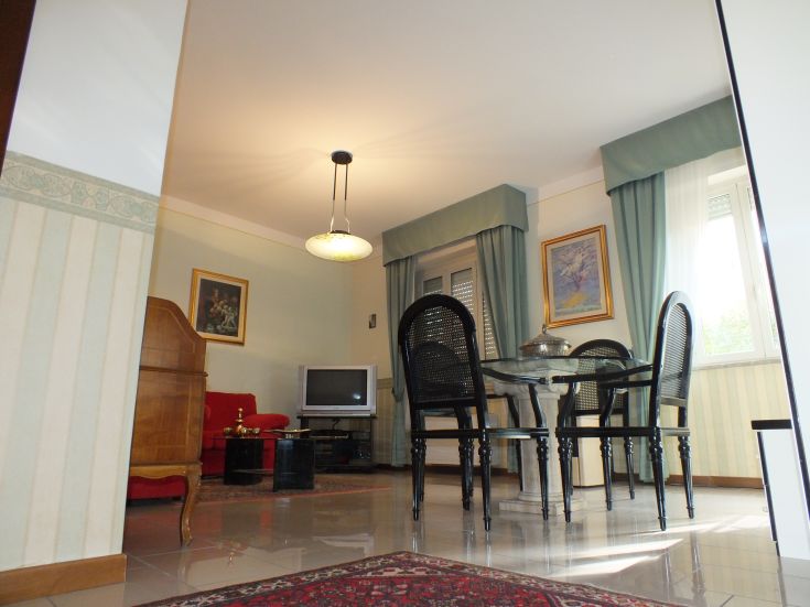 Un soggiorno semplice con una area relax e una sala da pranzo. La luce calda e i toni pastello creano un'atmosfera confortevole.