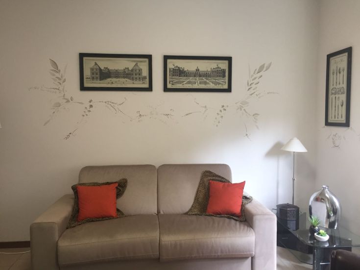 Un soggiorno confortevole con un divano beige e cuscini colorati. Elementi decorativi alle pareti.