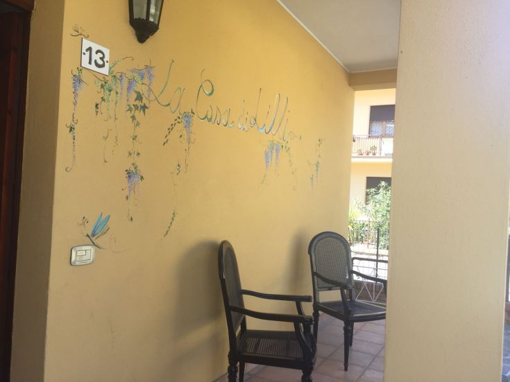 Un angolo accogliente con sedie su un portico, decorato con la scritta 