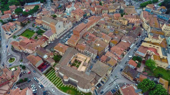 Panorama di una città storica con strade in pietra e tetti rossi.