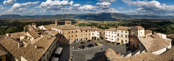 Panorama di un borgo italiano circondato da vegetazione e colline.
