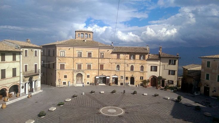 Una piazza tranquilla, circondata da palazzi storici, sotto un cielo nuvoloso.