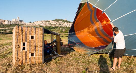 Un pallone aerostatico si sta preparando per il decollo all'alba in un bel paesaggio. Il cielo è luminoso e il terreno è tranquillo.