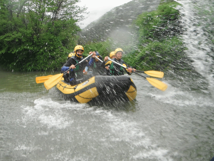 Un gruppo di persone pratica rafting in un fiume circondato da vegetazione.