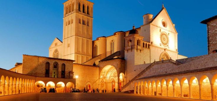 La Basilica di San Francesco appare illuminata mentre il crepuscolo avvolge la città.