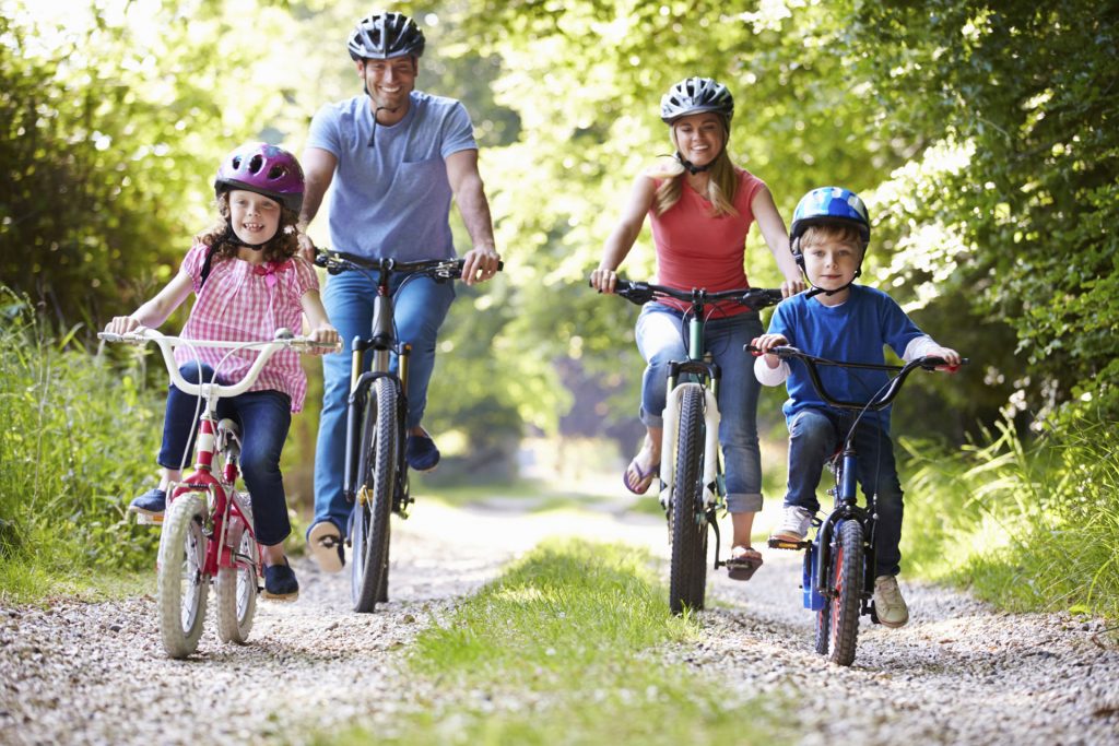 Una famiglia ride e si diverte in bicicletta su un sentiero immerso nel verde.