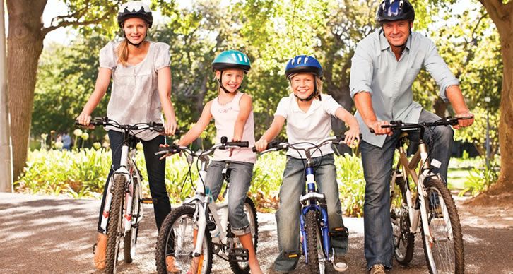Una famiglia serena gira in bicicletta in un parco, godendosi momenti semplici e spensierati all'aperto.