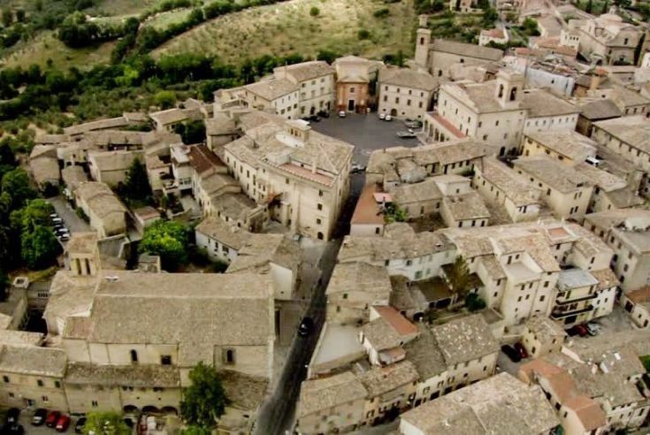 Panorama di un affascinante borgo storico, circondato da dolci colline verdi.