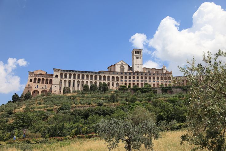 Abbazia circondata da vegetazione, con un panorama suggestivo delle colline umbre.