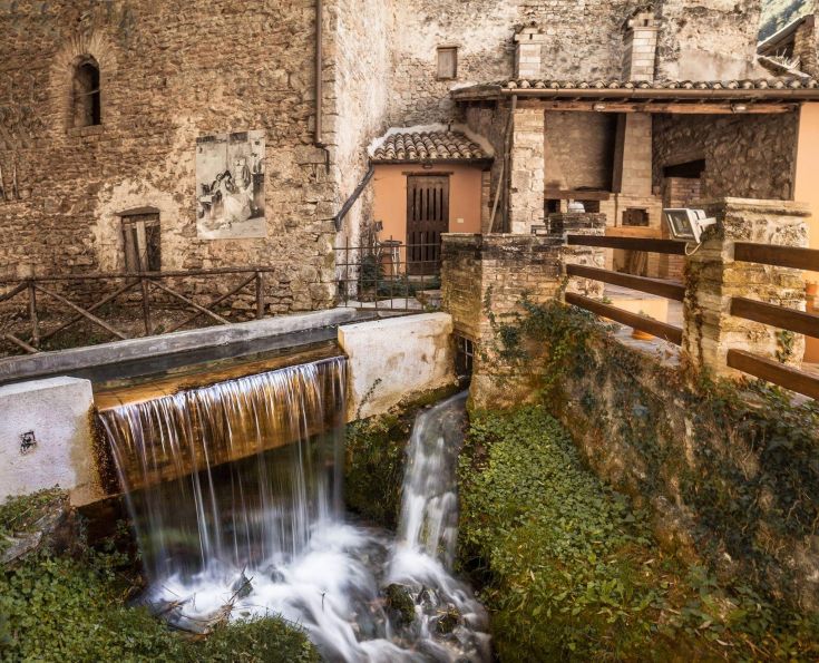 Un angolo caratteristico di un antico villaggio con cascate d'acqua che scorrono e palazzi storici.