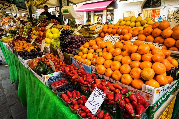 Un mercato vivace con una varietà di frutta fresca, dai pompelmi alle fragole, disposti in modo ordinato.