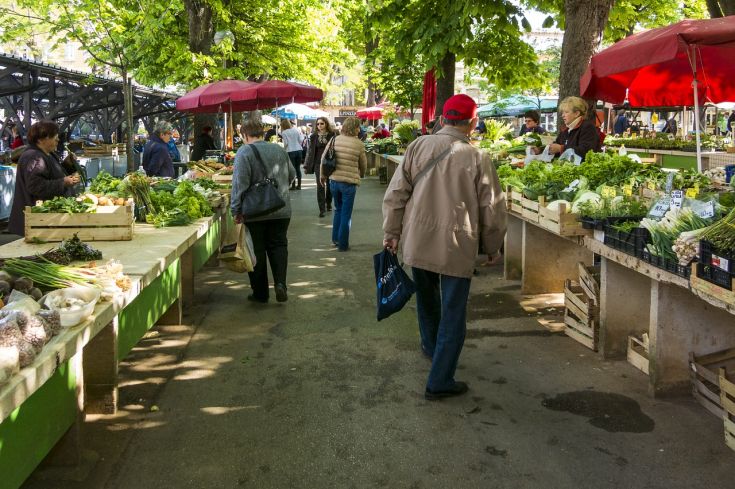 Un mercato all'aperto ricco di frutta e verdura fresca, con vari stand e visitatori che si godono l'atmosfera.