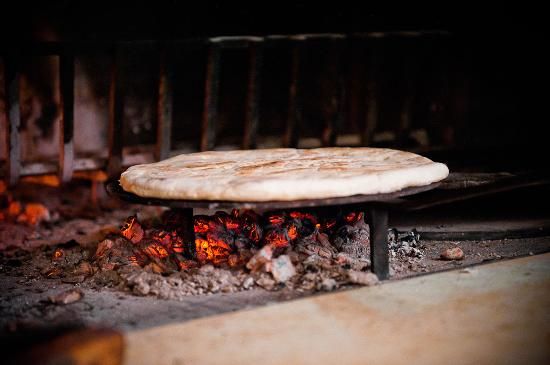  Torta al testo che cuoce su braci ardenti di un camino rustico.