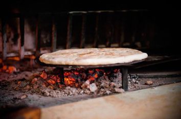 Una scena di pane che cuoce su braci ardenti in un forno rustico.