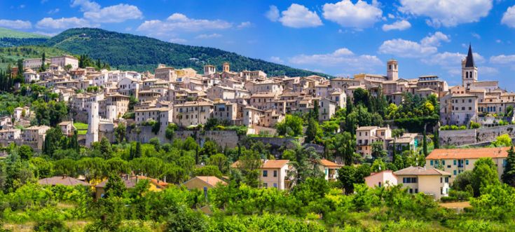 Un panorama di un antico borgo immerso nel verde, sotto un cielo sereno.