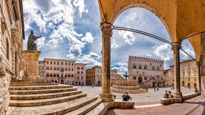 Scena della storica Piazza IV Novembre, centro di Perugia, con nuvole nel cielo.