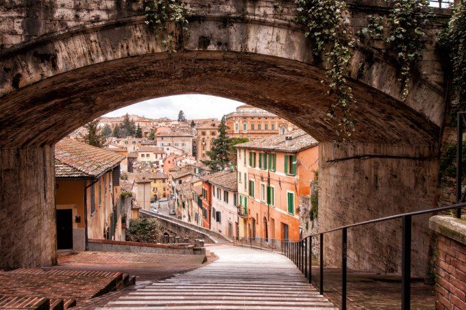 Un tranquillo vicolo di una città storica, caratterizzato da edifici antichi e da un ponte in pietra.